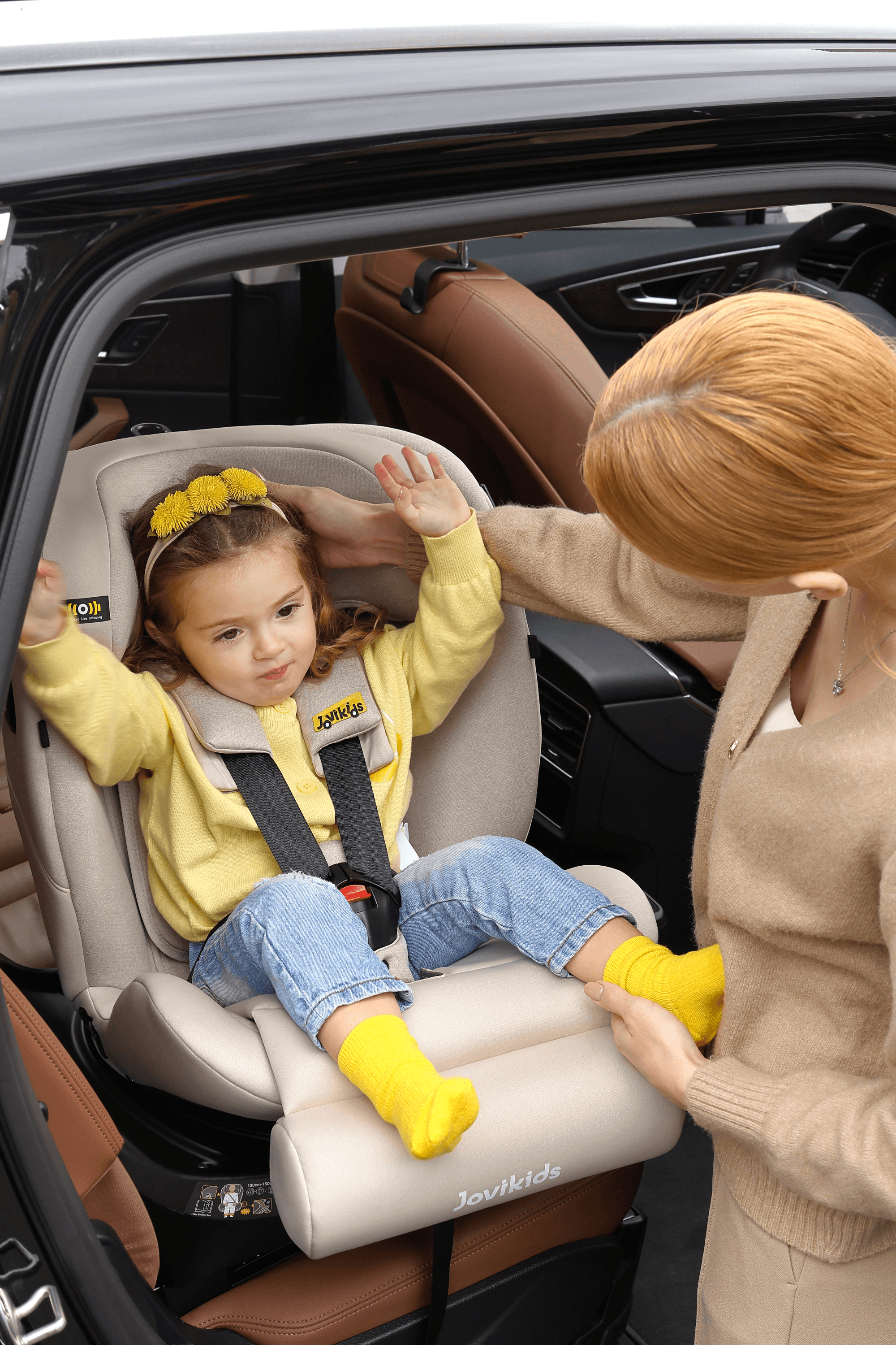Parent settling a child into a Jovikids car seat