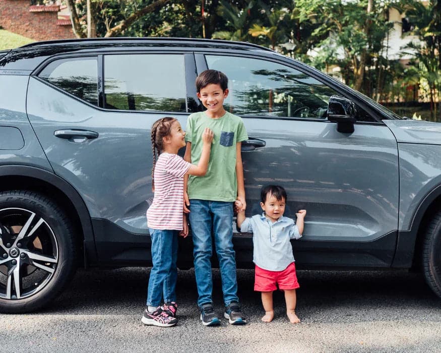 Three children beside a family car with TinySeats