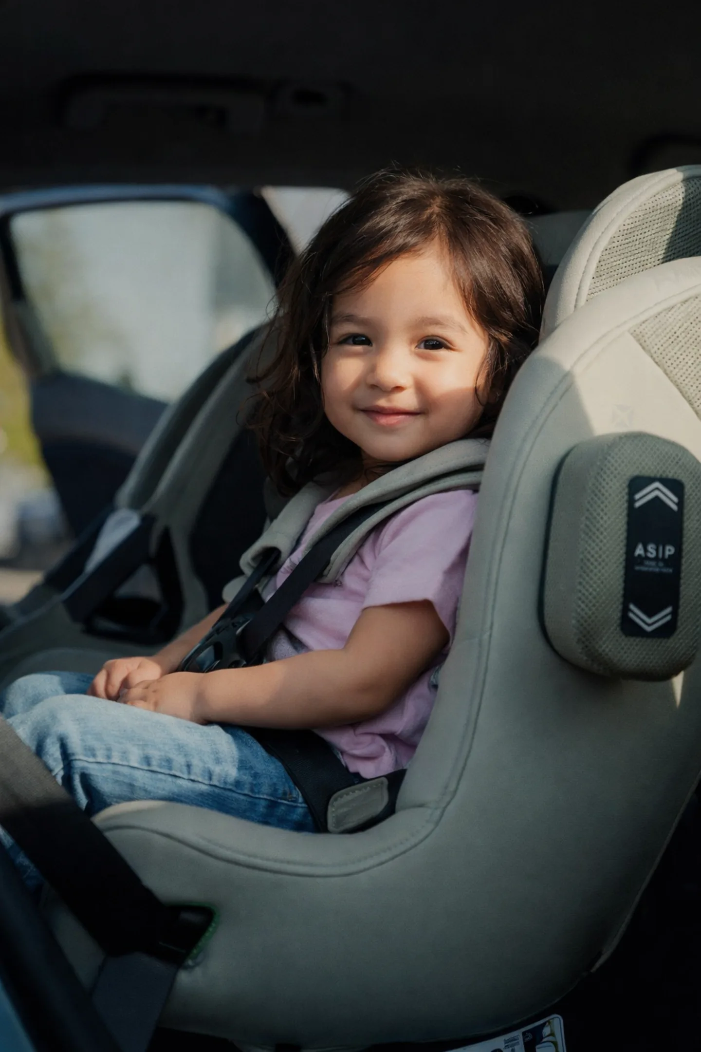Young child smiling safely in a rear-facing car seat